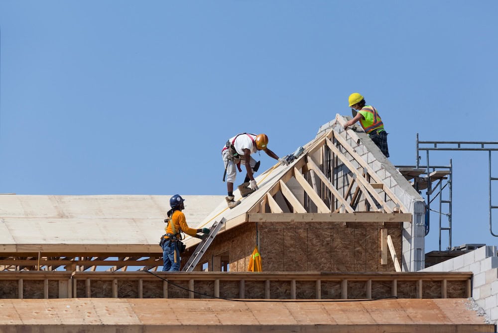 Construction workers building a house roof structure
