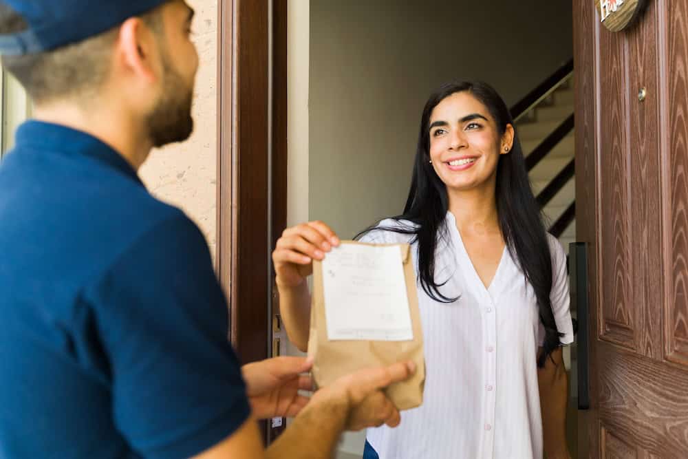 Smiling woman receiving a food delivery at her doorstep