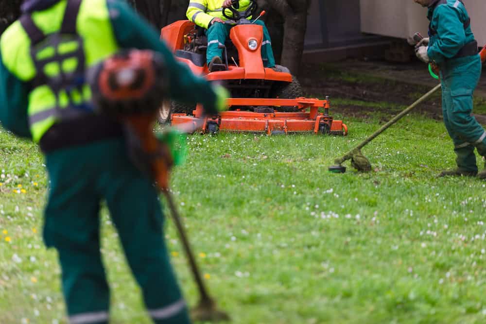 Ground maintenance workers mowing grass with lawn equipment