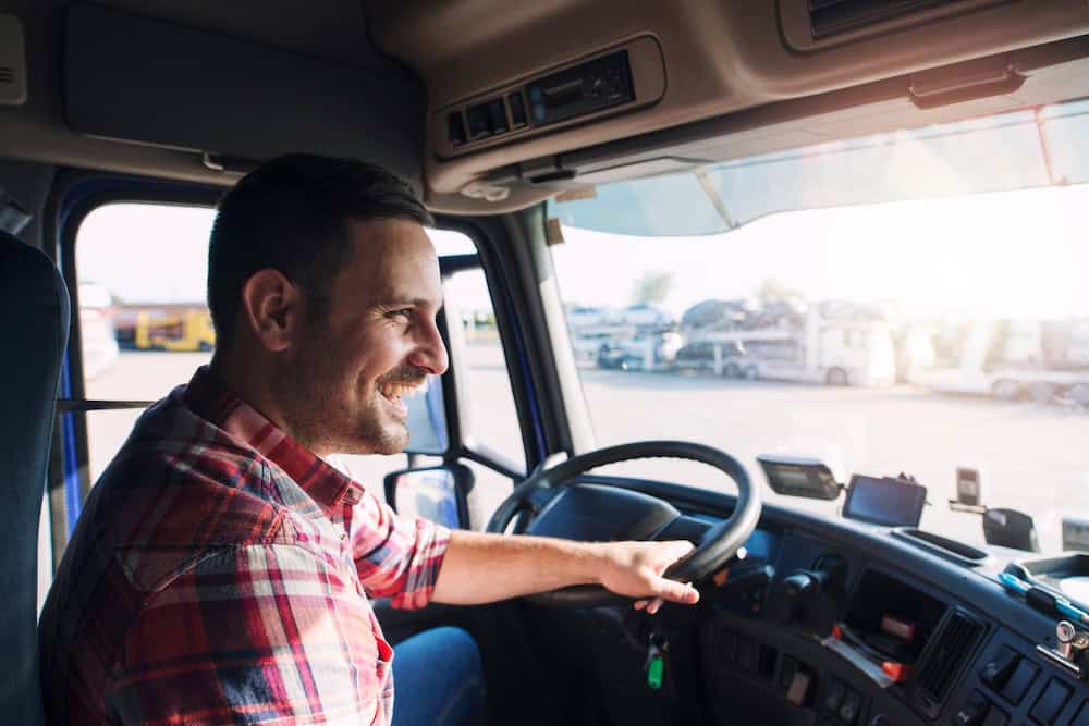 Truck driver smiling while driving a commercial vehicle