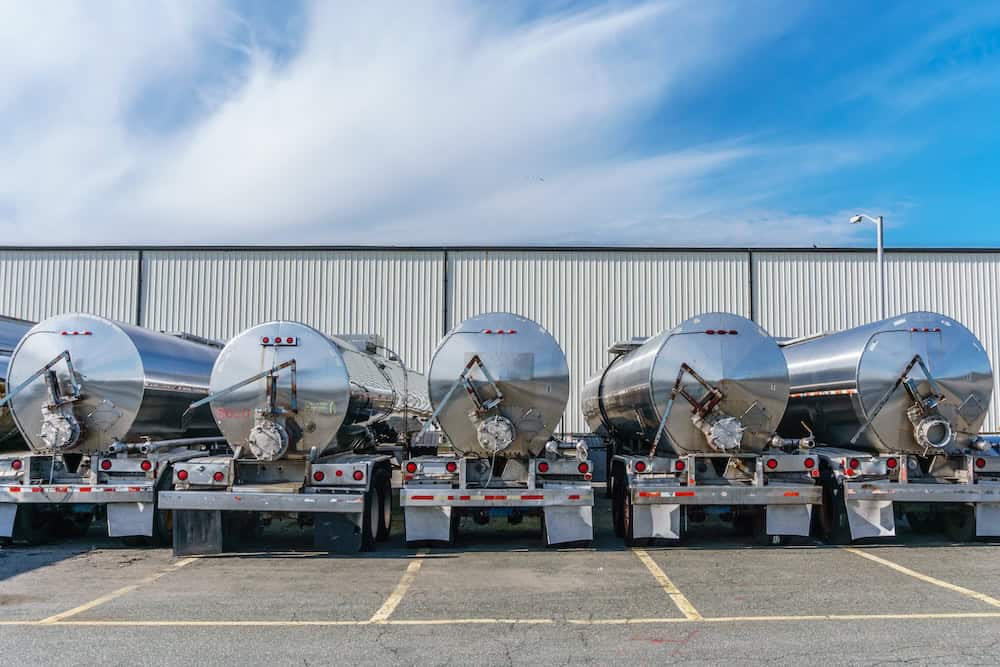 Row of stainless steel tanker trucks parked at a facility