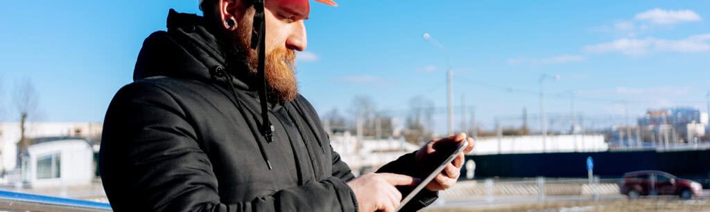 Man looks and interacts with tablet outside in cold and snow conditions