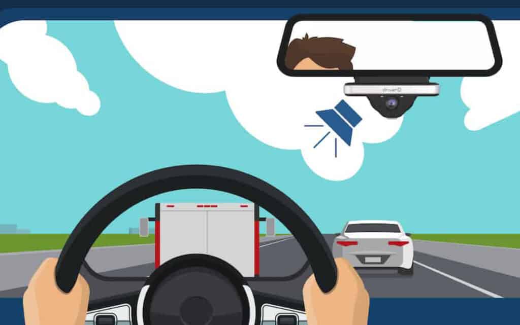 View from behind steering wheel of traffic on a road and an alarm from the dashcam.