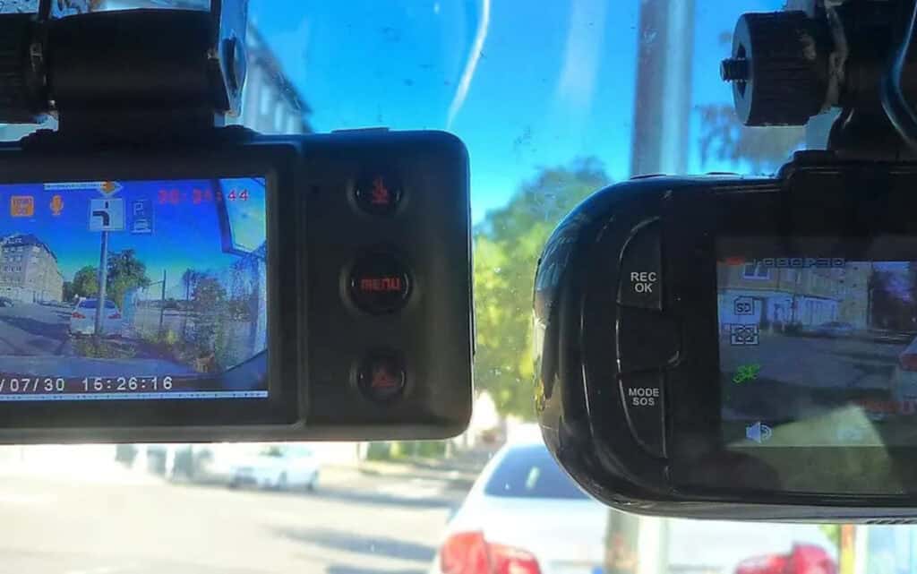 Two dashcams hanging side-by-side in a vehicle.