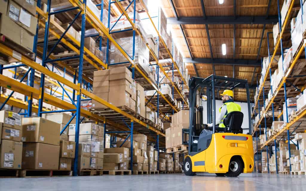A forklift in a warehouse loading boxes onto shelves.