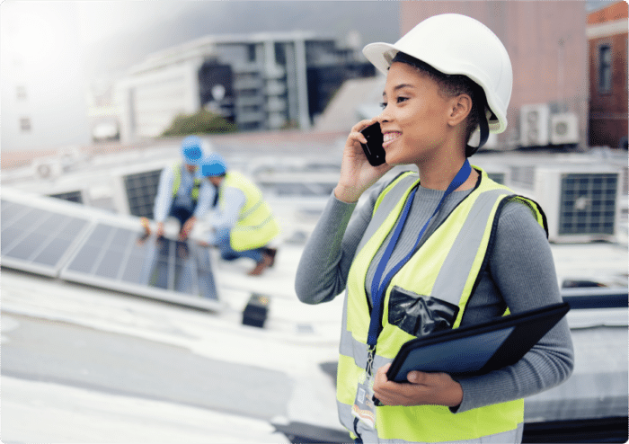 A happy utility worker on the phone at a project and using a tablet